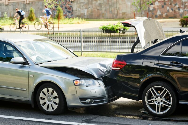 silver car with front end smashed under black cars back end