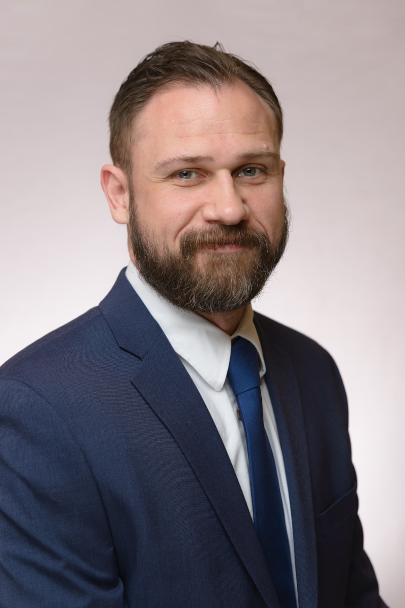 headshot of partner attorney Zachary Beriloff, a handsome 40-something white man with a trimmed beard wearing a navy blue suit