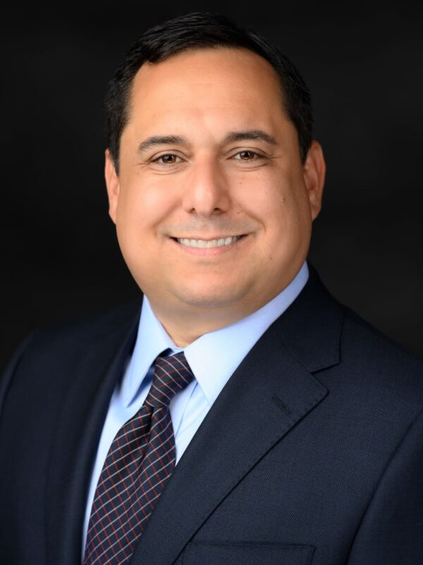 headshot of attorney John-Paul Puma, a smiling dark haired man in a dark suit and tie