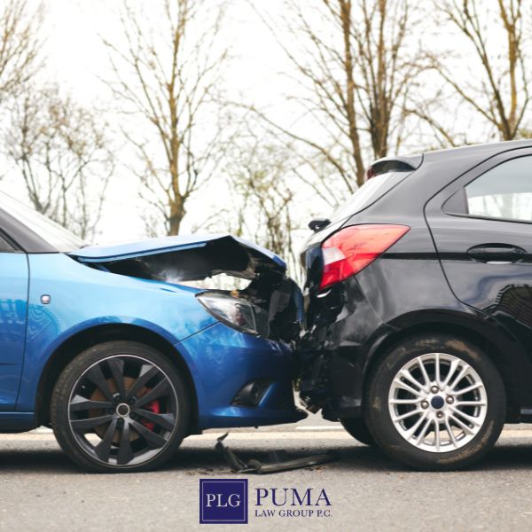 A blue car has rear-ended a black car on a road, causing visible damage to both vehicles. Trees and cloudy sky are in the background. Puma Law Group logo is at the bottom, highlighting trusted car accident lawyer in Commack services.