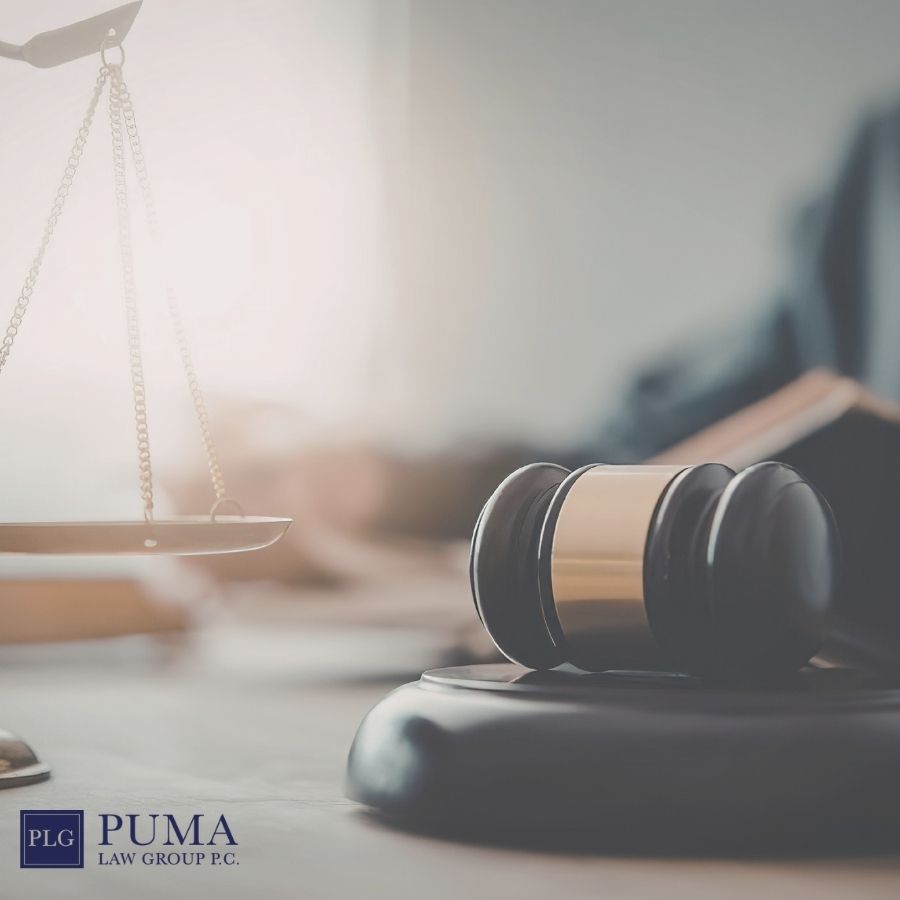 A wooden judge's gavel and a set of legal scales rest on a desk with law books in the background, reflecting the expertise of a car accident lawyer in Holbrook. The Puma Law Group P.C. logo appears in the bottom left corner. A wooden judge's gavel and a set of legal scales rest on a desk with law books in the background, reflecting the expertise of a car accident lawyer in Holbrook. The Puma Law Group P.C. logo appears in the bottom left corner.