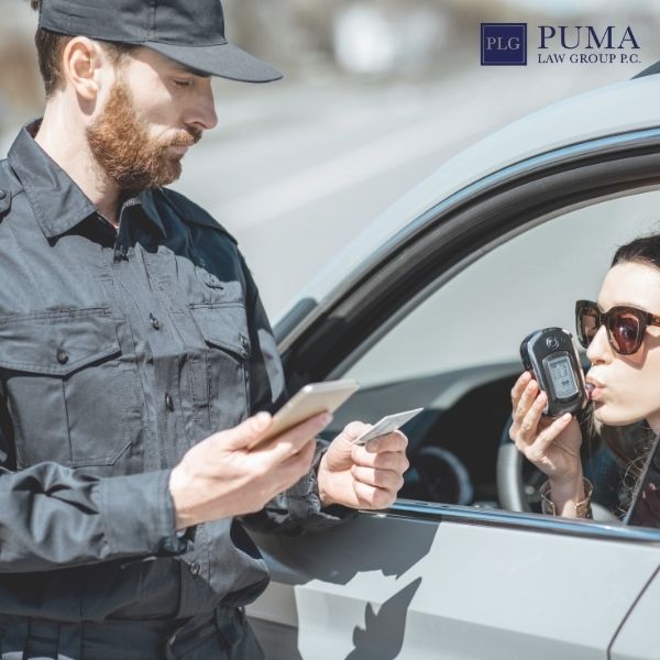 A police officer holds a device while a woman in a car blows into a breathalyzer; the Puma Law Group P.C. logo is visible, highlighting the trusted car accident lawyer in Commack.